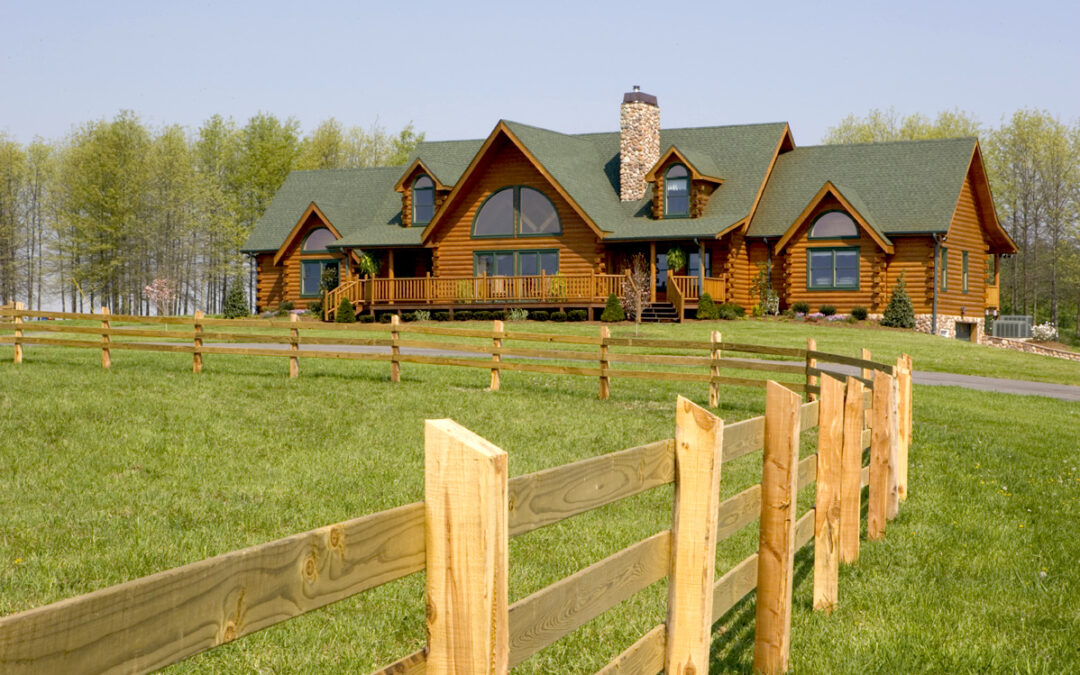 log home with two extensions on either side of the large living space. the home is round log with green metal roof