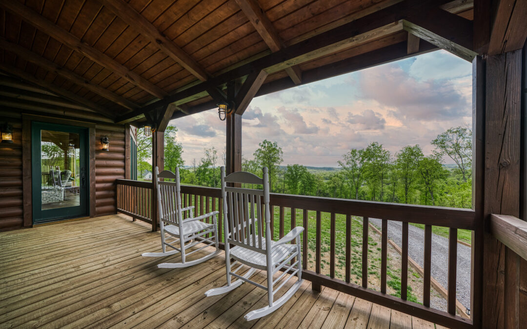 photo of covered porch with wood ceiling and round wood walls of log home